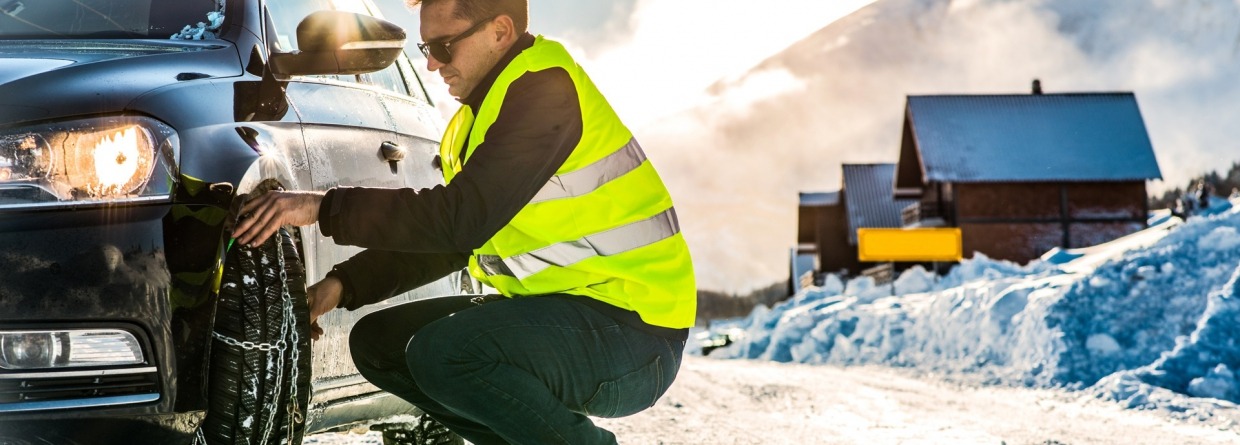 Man legt sneeuwketting aan op z'n auto