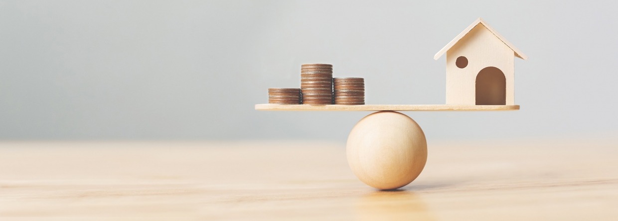 Houten huis en geld munten op hout schaal. Investeringen huis hypotheek